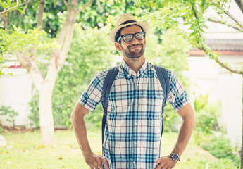 Happy young bearded wearing eye glasses man carrying his backpack preparing to travel.