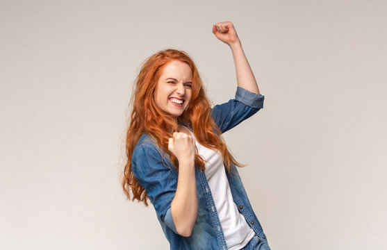 Millennial Girl Shaking Fists Celebrating Success On Light Studio Background