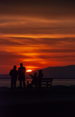 Fototapeta na wymiar People near seaside in sunset silhouetteof people.
