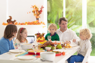 Family with kids at Thanksgiving dinner. Turkey.