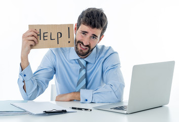 Depressed sad and frustrated young businessman holding a help sign in stress at workplace