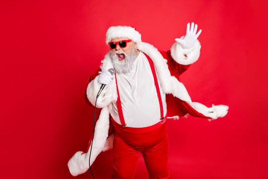 Portrait of cool funny fat overweight santa claus with big belly sing song on christmas party wear style stylish trendy eyeglasses eyewear hat isolated over red background