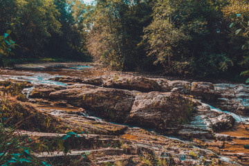 Strong water stream in the high mountain area surrounded by stones with small moss islands in the water body.