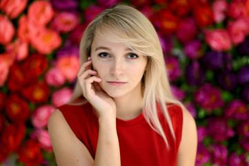 Obraz na płótnie Canvas Portrait of a pretty blonde girl in a white blouse on a colored background. Right in front of the camera in various poses.