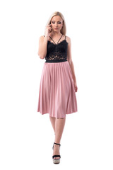 Serious busy elegant young woman walking and talking on the phone looking down. Full body isolated on white background.