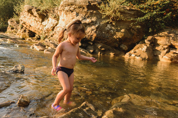 Little cute beautiful girl swims in a mountain river. 2019
