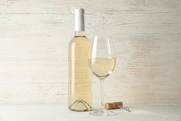 Corkscrew, bottle and glass with wine on white wooden background, copy space