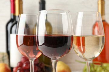 Grape, bottles and glasses with wine on white background, close up