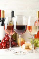 Fruits, cheese, bottles and glasses with different wine on white background, space for text
