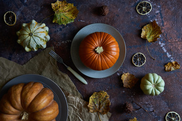 Pumpkin on a plate. Autumn cozy background with leaves, vanilla.