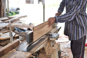 Carpenter planing wood surface with planer machine. Woodworking tools and technology.