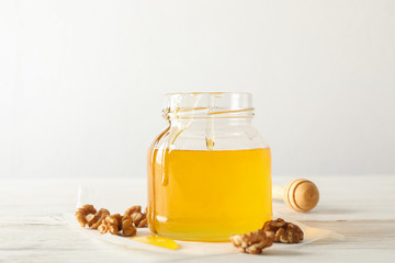 Walnuts, dipper, parchment and glass jar with honey on white background, copy space