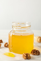 Walnuts, dipper, parchment and glass jar with honey on white background, copy space