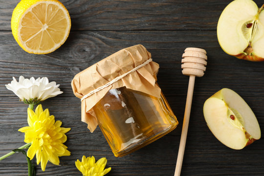 Dipper, apple, lemon, flowers and jar with honey on wooden background, top view
