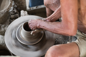 Close up of professional potter's hand working on pottery wheel.