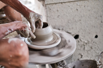 Close up of professional potter's hand working on pottery wheel.