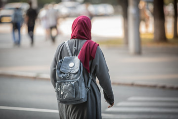 A student from an Arab country walks in a European city. A girl of Arab appearance walks around the city. European student from an Arab country.