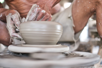 Close up of professional potter's hand working on pottery wheel.