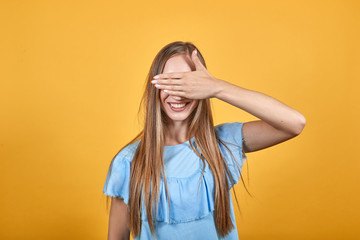 girl brunette in blue t-shirt over isolated orange background shows emotions