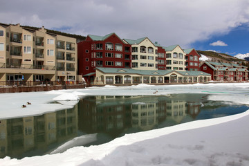 Obraz premium Colorado nature background, ski resort vacation concept. Scenic view with Keystone sky resort downtown and mountains around the covered by snow and thawed ice lake in spring sunlight. 