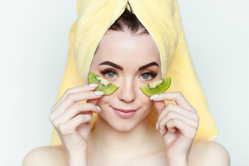 Portrait of young beautiful woman with healthy glow perfect smooth skin holds two piece of kiwi...