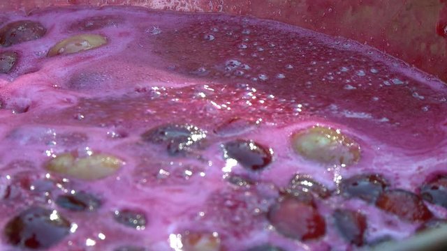 Handheld, close up shot of boiling sauce of berries and apples.