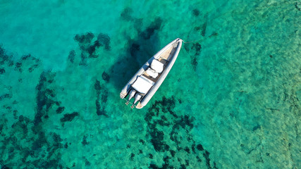 Aerial top view luxury inflatable rib speed boat docked in mediterranean emerald bay with crystal clear sea