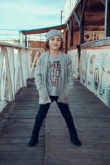 A fashionable little girl in a knitwear by the sea in the fall