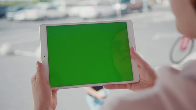 Close up hands woman using tablet device computer with green screen outdoors in street at sunlight horizontal bloom message pad technology chroma key female digital girl app chat finger slow motion