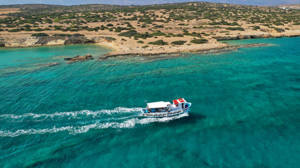 Aerial drone photo of picturesque and traditional tourist vessel cruising in famous beaches of Koufonisi island, Small Cyclades, Greece
