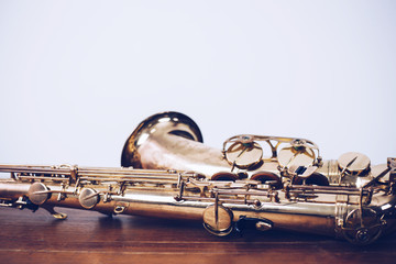 close up of  saxophone on wooden table with white wall texture background, music background with...