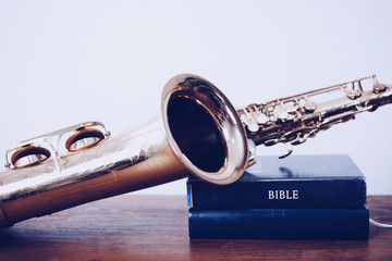 close up of bible with saxophone on wooden table with white wall texture background, Christian...