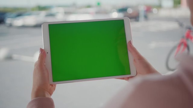 Close up hands woman using tablet device computer with green screen outdoors in street at sunlight horizontal bloom message pad technology chroma key female digital girl app chat finger slow motion