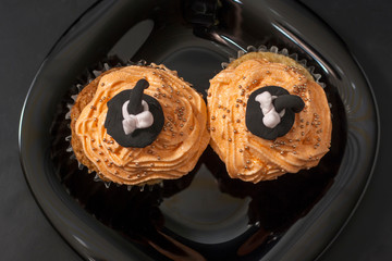 Happy Halloween orange and black decorated cupcake with a black witch hat and butter cream with beads on a black plate.