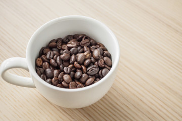 fresh roasted coffee beans in white cup on wood table