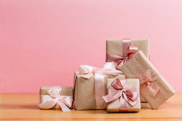 set of beautiful different gift boxes made by handmade with pink bows on a wooden table with a pink background. flat lay