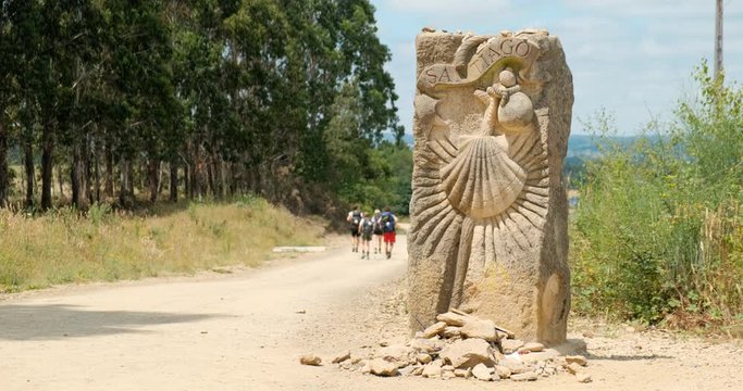 Pilgrims walking on a dirt path in countryside near Santiago de Compostela, Spanish town at the end of Camino de Santiago or Way of St James. Family hiking on the road in Spain