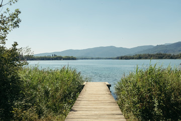 Wooden path on the shore of a blue lake in Banyoles Catalonia under a sunny blue sky on a summer landscape