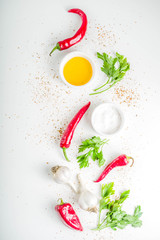 Herb and spices cooking background. Olive oil, salt, garlic, parsley, hot red peppers chili, for cooking  homemade dinner. On a white background, copy space top view