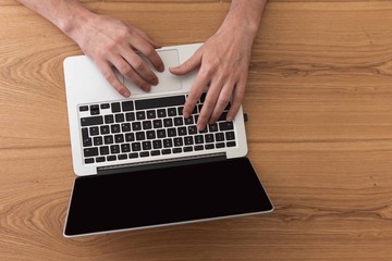 Fototapeta na wymiar Man working on laptop, top view on male hands using laptop