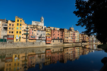 Fototapeta na wymiar Girona city skyline with river houses colourful facades reflected on quiet river water on a blue summer sunny sky