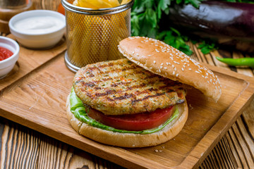 Burger with chicken and fries with sause on the board