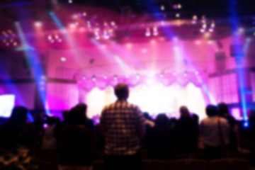 Fototapeta na wymiar Blurred of Christian Congregation Worship God together in Big Church hall in front of music stage and light effected.