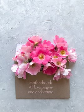 Pink flowers in an envelope marked Motherhood: All love begins and ends there