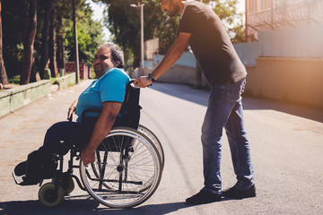 Happy man in wheelchair and him friend outdoors