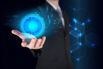 Businessman holding the glowing bitcoin currency digital icon on light hexagonal background as business, innovation, intelligent, investment, stock and income concept.