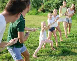 Ordinary kids with parents playing tug of war