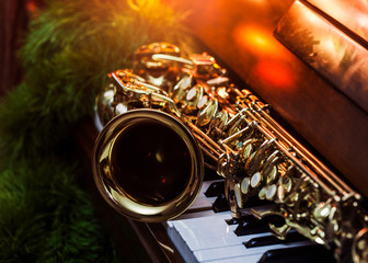 close up of alto saxophone  on the Piano Keys with Christmas tree and decoration light, in the...