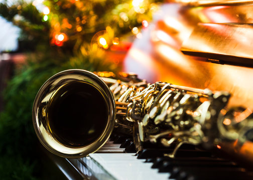 close up of alto saxophone  on the Piano Keys with Christmas tree and decoration light, in the night of Christmas season, Christmas background