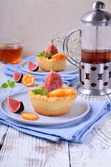 Grated mini pie with cottage cheese topped with pieces of figs and kumquats on ceramic plate